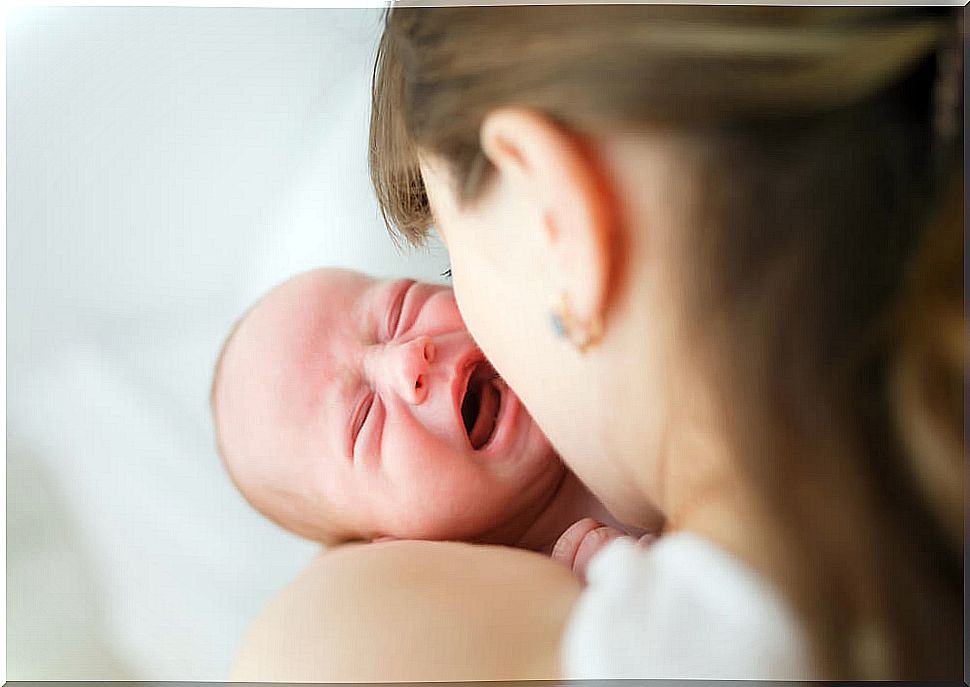 Crying baby hugs his mother